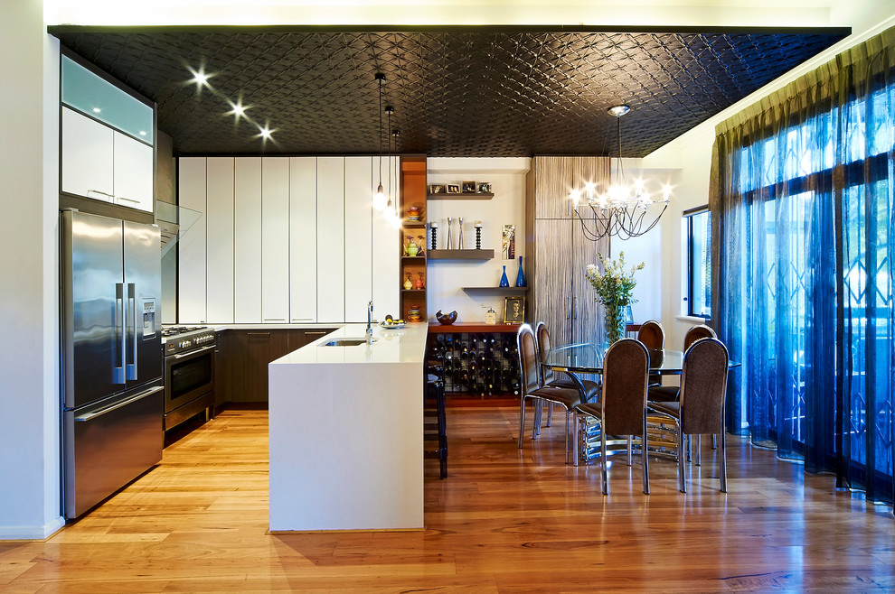 Immagine di una cucina contemporanea con lavello sottopiano, ante lisce, ante bianche, elettrodomestici in acciaio inossidabile e pavimento in legno massello medio