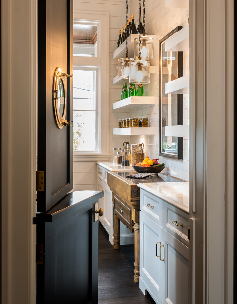 Imagen de cocina marinera con despensa, suelo de madera oscura, puertas de armario blancas y salpicadero de azulejos tipo metro