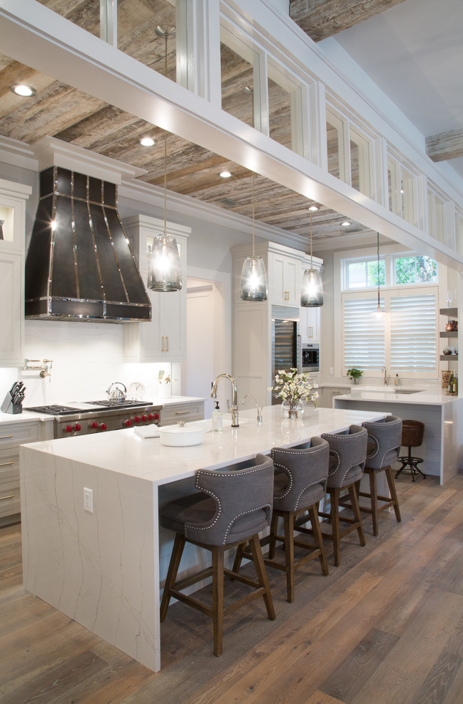 Landhaus Küche in L-Form mit Schrankfronten mit vertiefter Füllung, weißen Schränken, Küchenrückwand in Weiß, Küchengeräten aus Edelstahl, braunem Holzboden, Kücheninsel, braunem Boden und weißer Arbeitsplatte in Atlanta