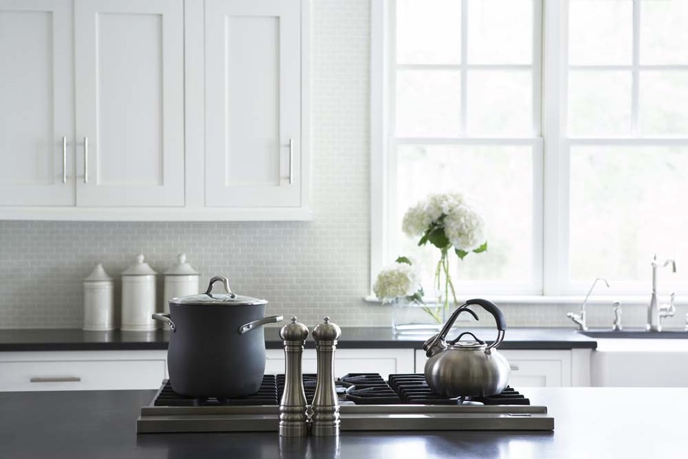 Eat-in kitchen - large traditional u-shaped eat-in kitchen idea in Charleston with a farmhouse sink, shaker cabinets, white cabinets, granite countertops, white backsplash, glass tile backsplash, stainless steel appliances and an island