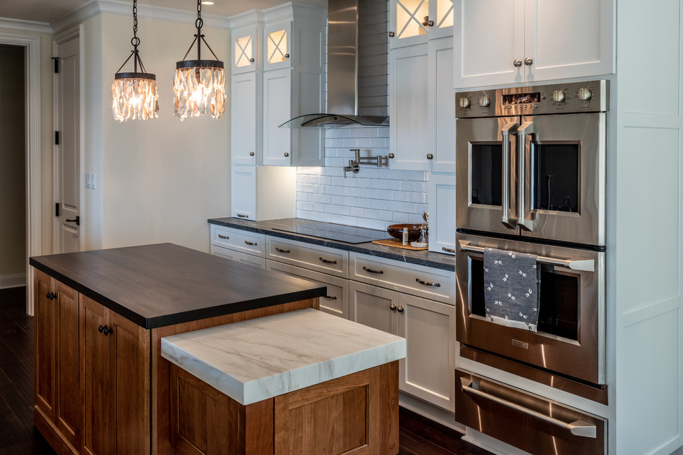 Mid-sized transitional galley enclosed kitchen photo in Charleston with a farmhouse sink, recessed-panel cabinets, white cabinets, granite countertops, white backsplash, ceramic backsplash, stainless steel appliances, an island and gray countertops