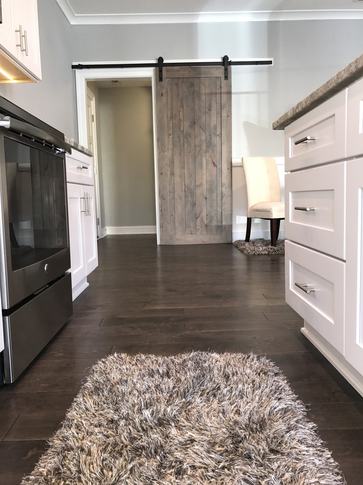 Mid-sized trendy galley dark wood floor and brown floor open concept kitchen photo in Other with shaker cabinets, white cabinets, granite countertops, stainless steel appliances and an island