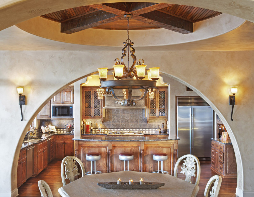 オースティンにある地中海スタイルのおしゃれなキッチン (シルバーの調理設備、レイズドパネル扉のキャビネット、濃色木目調キャビネット) の写真