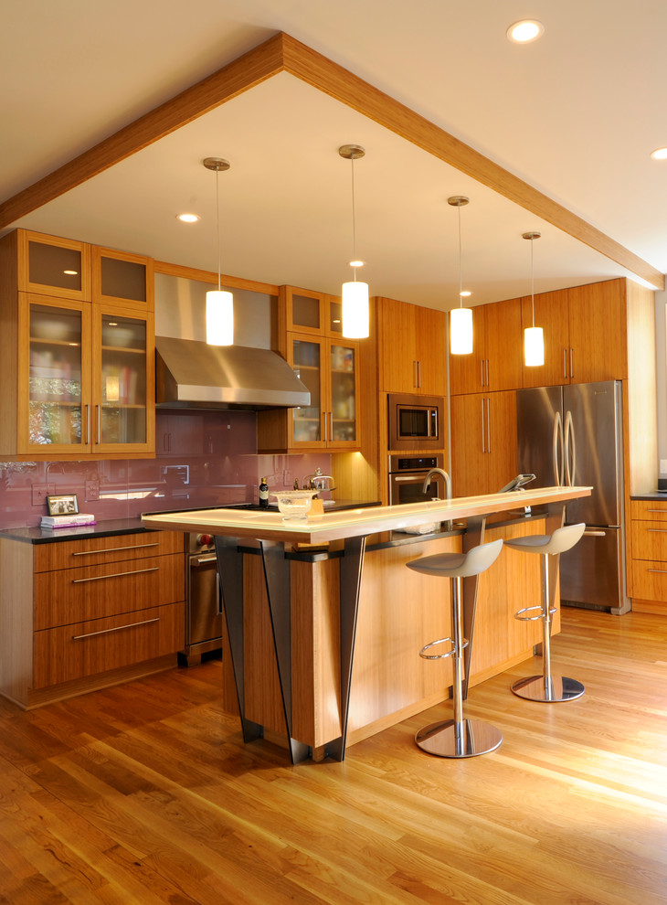 На фото: угловая кухня в стиле модернизм с стеклянными фасадами, фасадами цвета дерева среднего тона, стеклянной столешницей и техникой из нержавеющей стали