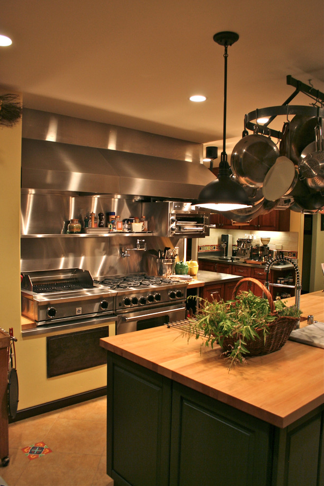 Idéer för ett avskilt, stort medelhavsstil u-kök, med en rustik diskho, luckor med upphöjd panel, skåp i mörkt trä, träbänkskiva, rostfria vitvaror, stänkskydd med metallisk yta, stänkskydd i metallkakel, klinkergolv i keramik och en köksö