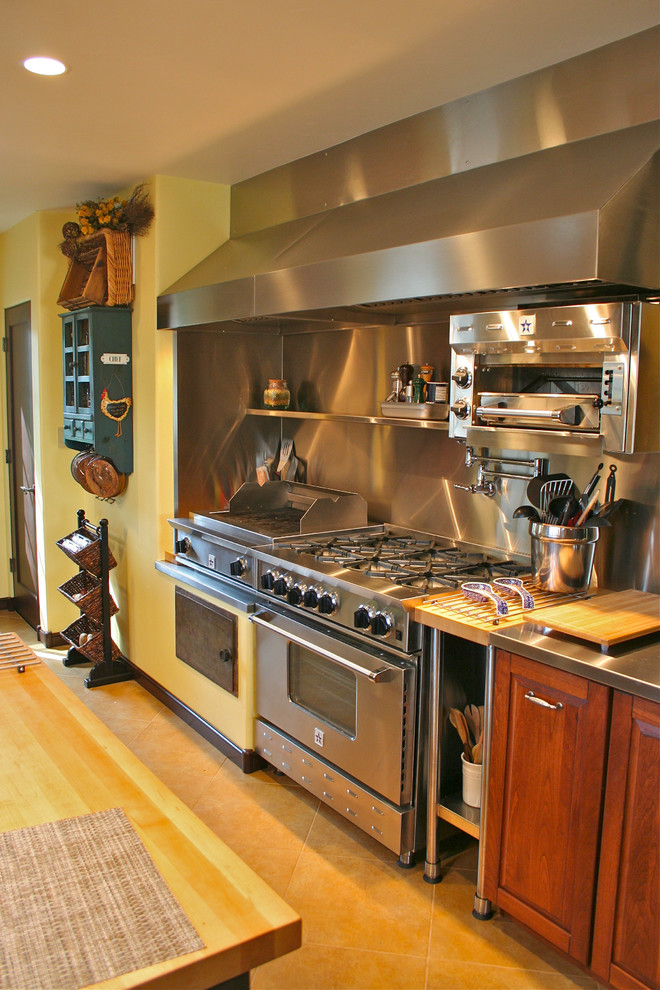 Geschlossene Mediterrane Küche in U-Form mit profilierten Schrankfronten, dunklen Holzschränken, Edelstahl-Arbeitsplatte, Küchenrückwand in Metallic und Küchengeräten aus Edelstahl in San Francisco