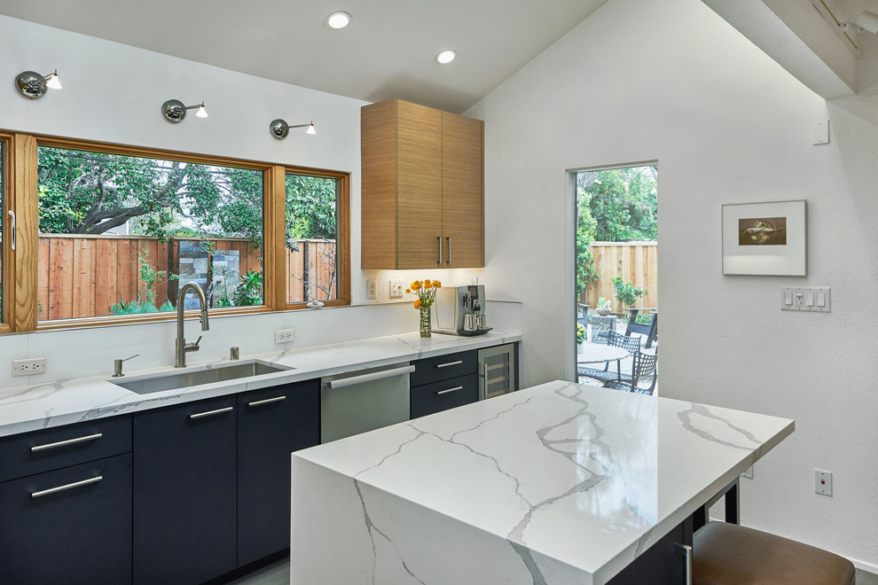 Inspiration for a mid-sized contemporary u-shaped slate floor and gray floor enclosed kitchen remodel in San Francisco with an undermount sink, flat-panel cabinets, light wood cabinets, marble countertops, white backsplash, glass sheet backsplash, stainless steel appliances, an island and white countertops
