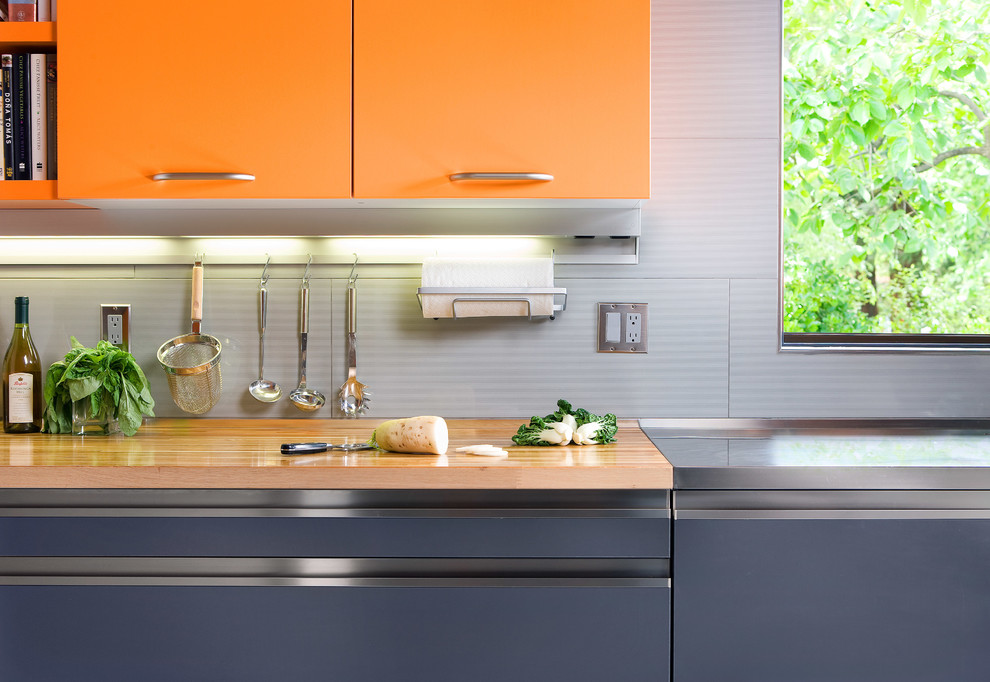 Idee per una cucina moderna di medie dimensioni con ante lisce, ante arancioni, top in acciaio inossidabile, paraspruzzi grigio, elettrodomestici in acciaio inossidabile, pavimento in cemento, pavimento grigio e top grigio