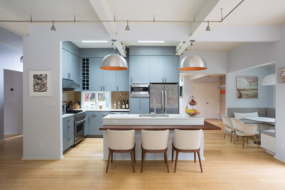 サンフランシスコにある広いミッドセンチュリースタイルのおしゃれなキッチン (アンダーカウンターシンク、フラットパネル扉のキャビネット、青いキャビネット、茶色いキッチンパネル、セラミックタイルのキッチンパネル、シルバーの調理設備) の写真