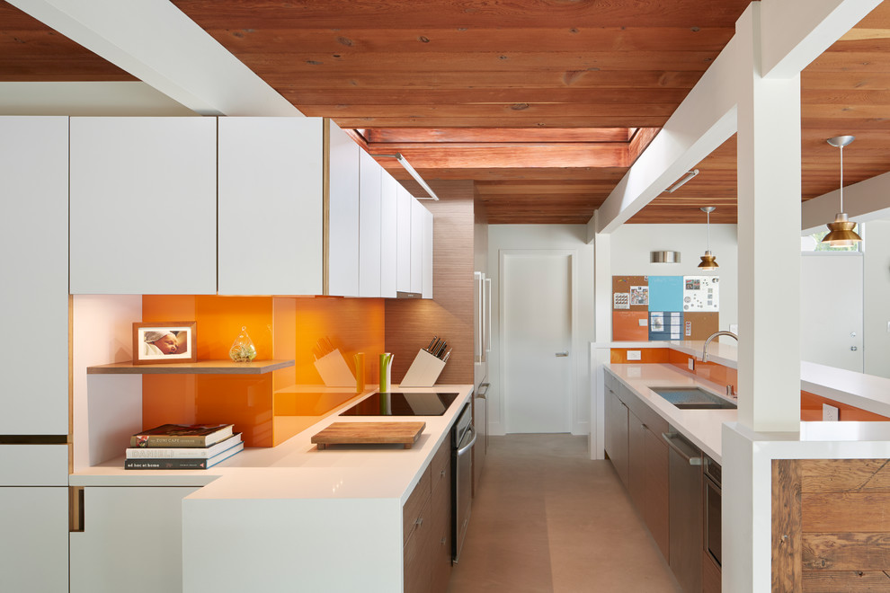 サンフランシスコにあるミッドセンチュリースタイルのおしゃれなアイランドキッチン (フラットパネル扉のキャビネット、白いキャビネット、オレンジのキッチンパネル、ガラス板のキッチンパネル) の写真