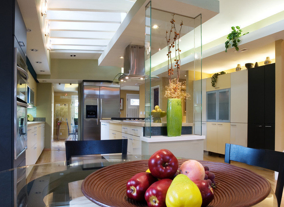 Moderne Küche mit Unterbauwaschbecken, flächenbündigen Schrankfronten, gelben Schränken, Kalkstein-Arbeitsplatte, Rückwand aus Glasfliesen, Küchengeräten aus Edelstahl, braunem Holzboden und Kücheninsel in San Francisco