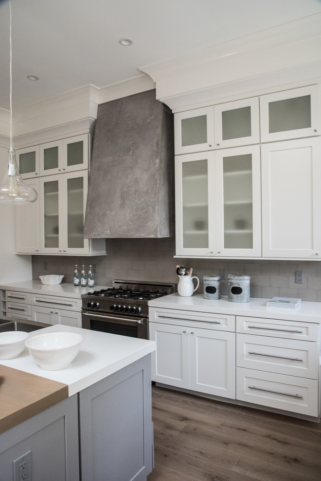 Immagine di una grande cucina minimal con ante di vetro, ante bianche e elettrodomestici in acciaio inossidabile
