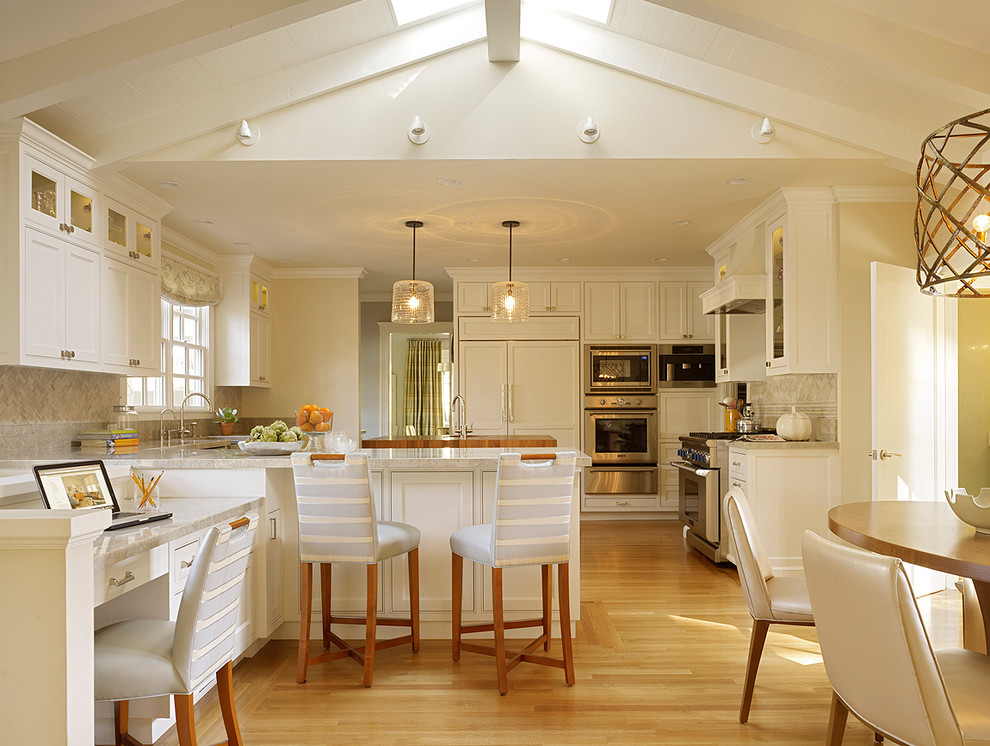 サンフランシスコにあるトランジショナルスタイルのおしゃれなキッチン (シェーカースタイル扉のキャビネット、白いキャビネット、ベージュキッチンパネル、シルバーの調理設備、淡色無垢フローリング) の写真