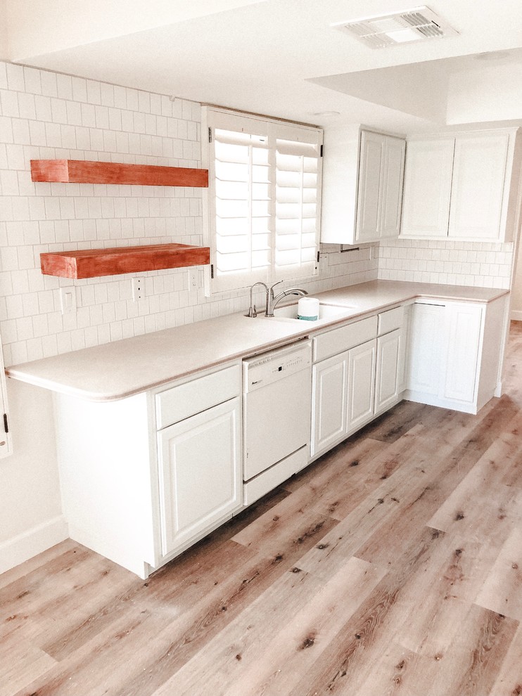 Idéer för mellanstora amerikanska brunt kök, med en undermonterad diskho, luckor med upphöjd panel, vita skåp, bänkskiva i koppar, vitt stänkskydd, stänkskydd i tunnelbanekakel, vita vitvaror, vinylgolv och brunt golv