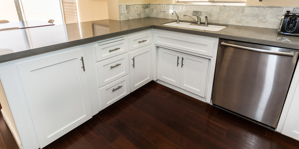 Modern inredning av ett kök, med en undermonterad diskho, luckor med infälld panel, vita skåp, flerfärgad stänkskydd, rostfria vitvaror, mörkt trägolv, en halv köksö, bänkskiva i kvartsit och stänkskydd i stenkakel