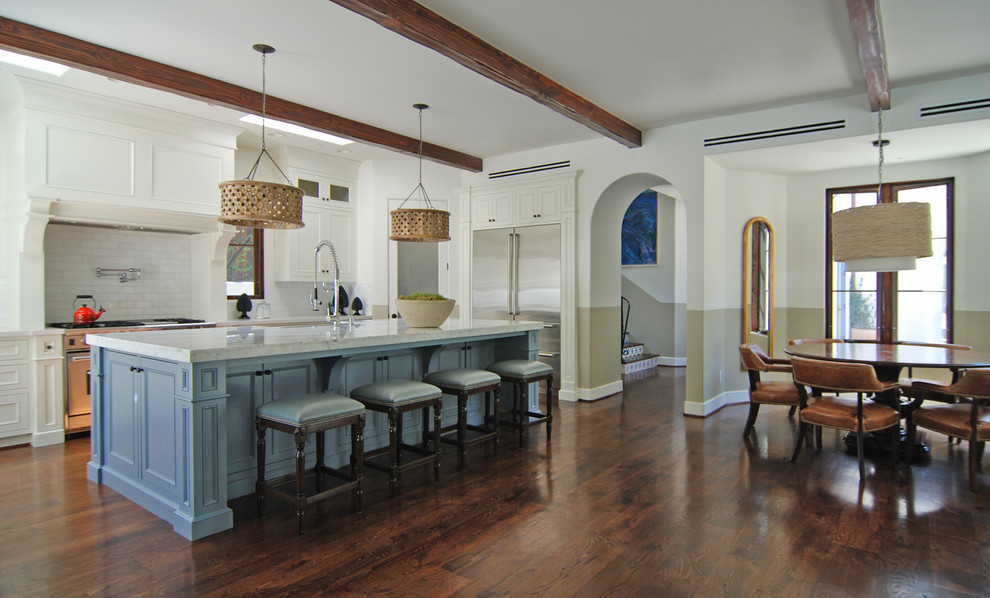 Inredning av ett medelhavsstil stort kök, med en undermonterad diskho, luckor med profilerade fronter, blå skåp, marmorbänkskiva, vitt stänkskydd, rostfria vitvaror, mellanmörkt trägolv och en köksö