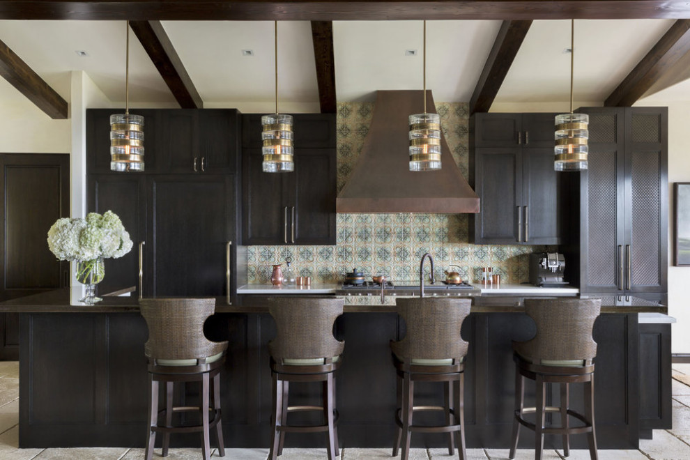 This is an example of a mediterranean galley kitchen in Los Angeles with shaker cabinets, dark wood cabinets, multi-coloured splashback, integrated appliances, an island, beige floors, black worktops and exposed beams.