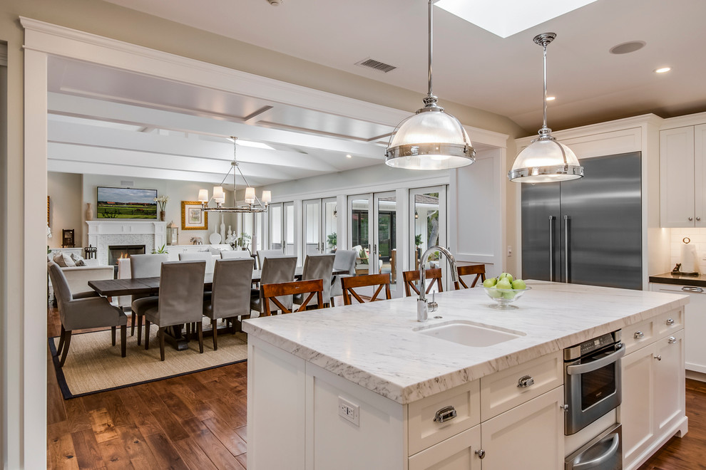 Large traditional u-shaped open plan kitchen in Los Angeles with an island, shaker cabinets, white cabinets, granite worktops, white splashback, ceramic splashback, stainless steel appliances and a belfast sink.