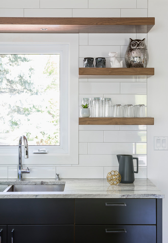 Bild på ett mellanstort funkis kök med öppen planlösning, med en undermonterad diskho, släta luckor, grå skåp, granitbänkskiva, vitt stänkskydd, stänkskydd i keramik, rostfria vitvaror, ljust trägolv och brunt golv