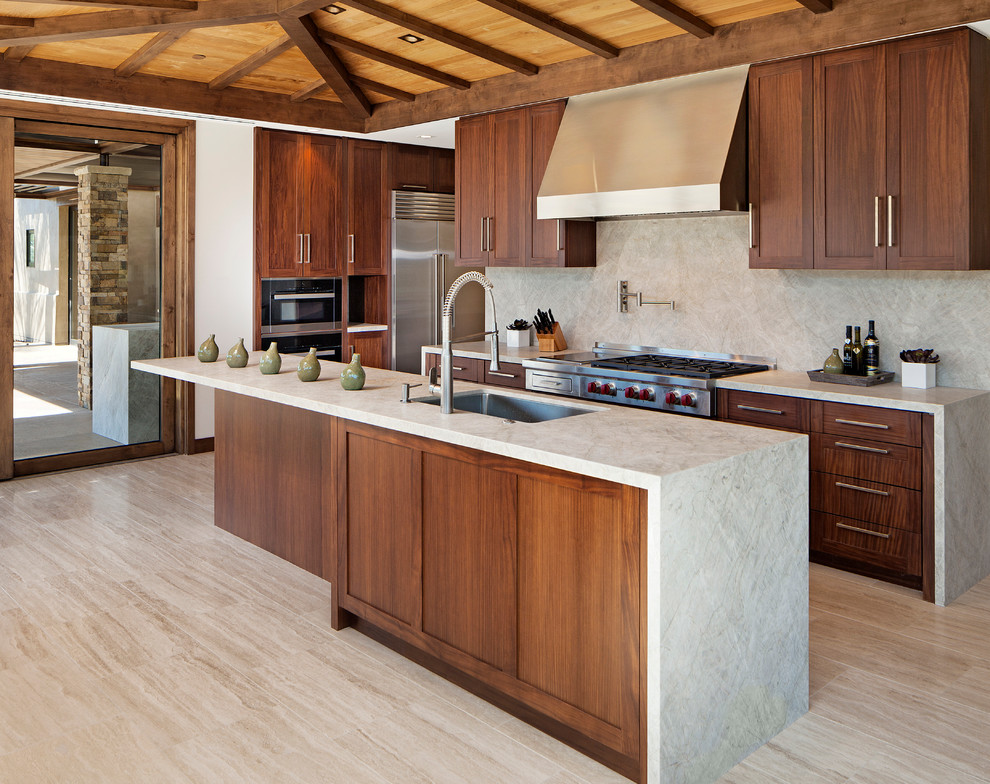 Exempel på ett modernt kök, med en undermonterad diskho, skåp i shakerstil, skåp i mörkt trä, grått stänkskydd, rostfria vitvaror, en köksö och travertin golv
