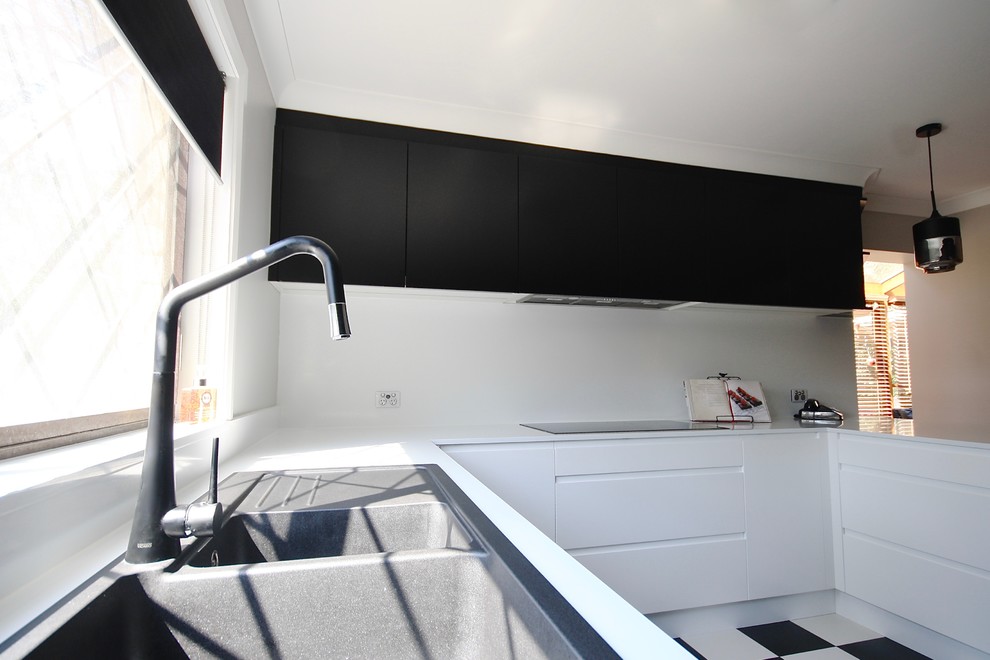 シドニーにある高級な中くらいなモダンスタイルのおしゃれなキッチン (ドロップインシンク、フラットパネル扉のキャビネット、黒いキャビネット、クオーツストーンカウンター、白いキッチンパネル、石スラブのキッチンパネル、黒い調理設備、セラミックタイルの床、黒い床) の写真