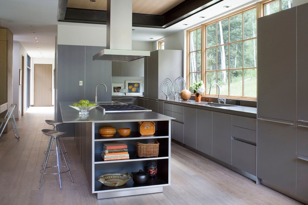Modelo de cocina actual con fregadero bajoencimera, armarios con paneles lisos, puertas de armario grises, encimera de acero inoxidable y electrodomésticos con paneles