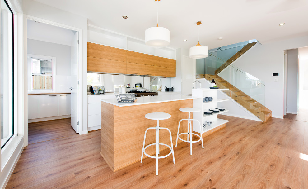 Moderne Küche mit flächenbündigen Schrankfronten, hellbraunen Holzschränken, braunem Holzboden und Kücheninsel in Brisbane
