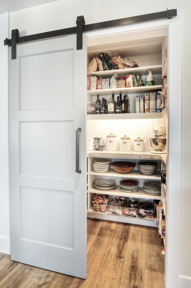 Exemple d'une grand arrière-cuisine chic avec un évier encastré, des portes de placard blanches, un plan de travail en granite, un électroménager en acier inoxydable, un sol en bois brun, une crédence en carrelage métro et un placard sans porte.