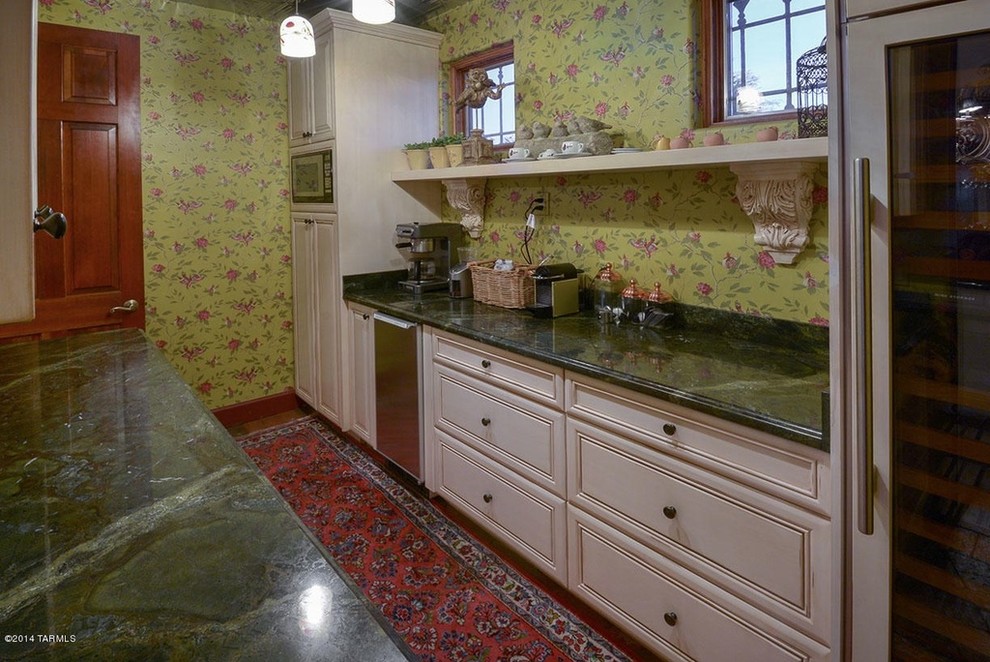 Lantlig inredning av ett stort kök, med en rustik diskho, luckor med infälld panel, svarta skåp, granitbänkskiva och tegelgolv