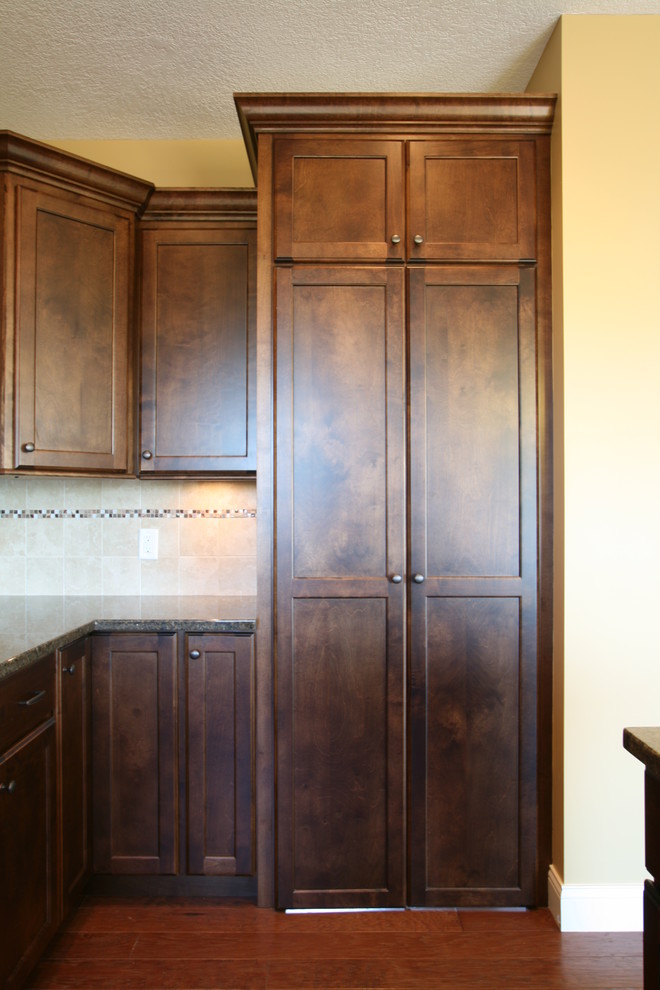 Exemple d'une cuisine américaine chic en L et bois foncé avec un placard à porte plane, une crédence beige et une crédence en céramique.