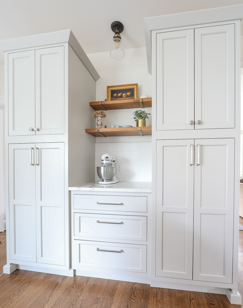 Inspiration for a large traditional u-shaped kitchen pantry in New York with a submerged sink, beaded cabinets, grey cabinets, quartz worktops, white splashback, metro tiled splashback, stainless steel appliances, medium hardwood flooring, an island and white worktops.