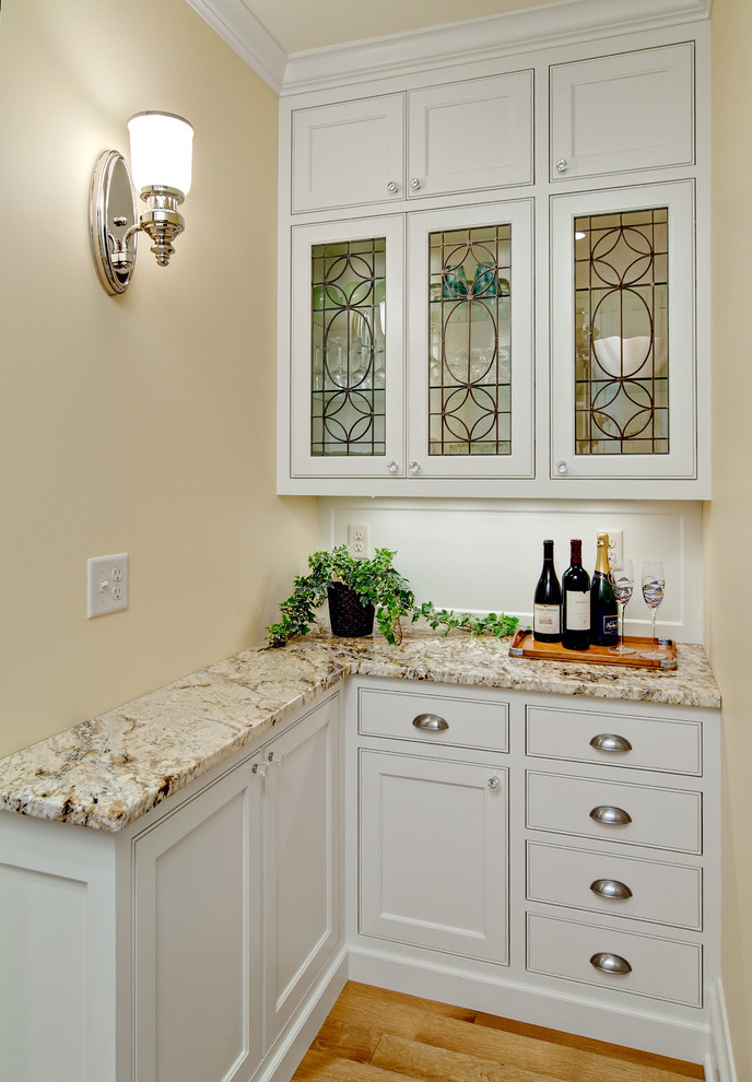 Cette image montre une petite cuisine traditionnelle en L avec un placard à porte affleurante, des portes de placard blanches, un plan de travail en granite et une crédence blanche.