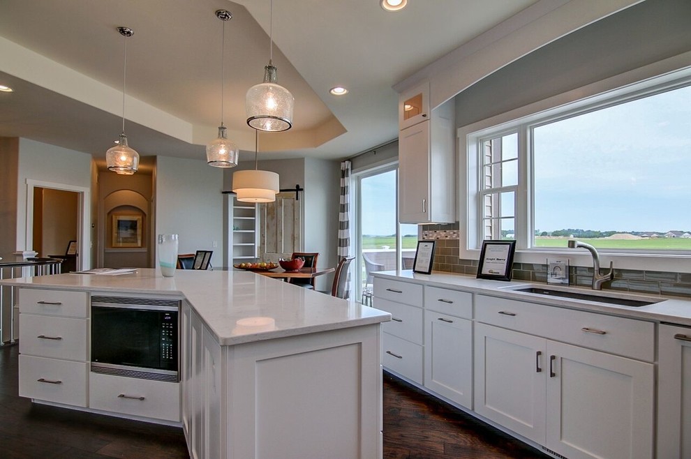 Example of a large transitional u-shaped laminate floor and brown floor eat-in kitchen design in Other with an undermount sink, white cabinets, gray backsplash, subway tile backsplash, stainless steel appliances and an island