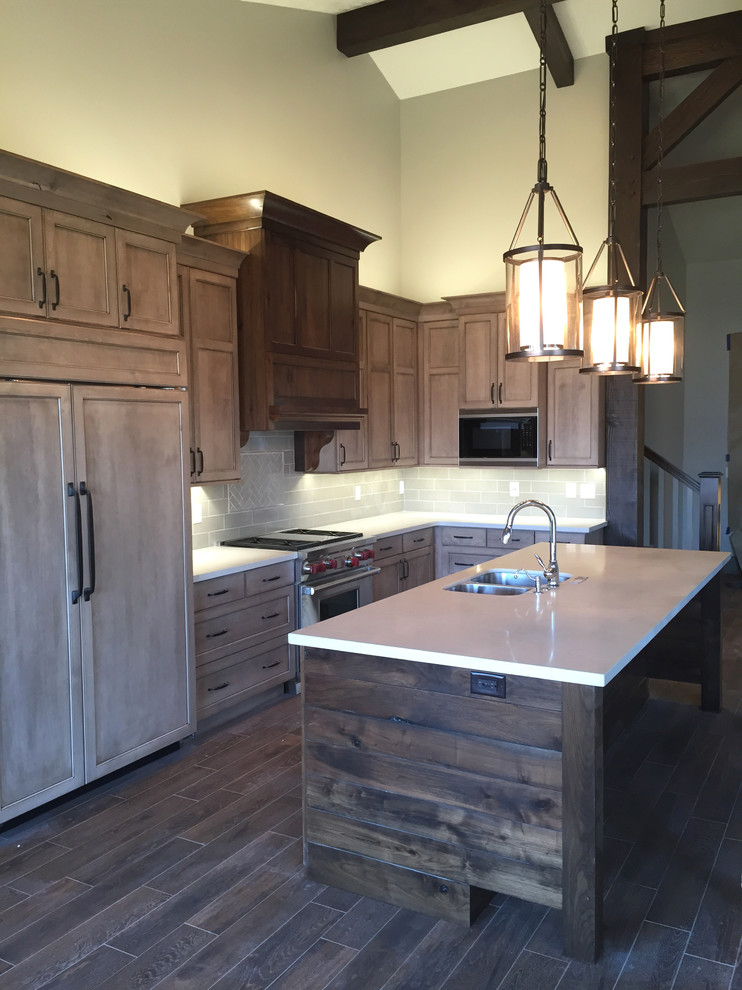 Eat-in kitchen - mid-sized rustic galley medium tone wood floor eat-in kitchen idea in Salt Lake City with shaker cabinets, brown cabinets, solid surface countertops, beige backsplash, ceramic backsplash, stainless steel appliances and an island