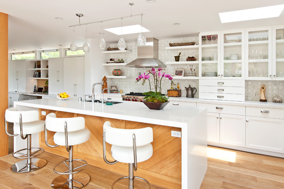 Contemporary galley kitchen in Los Angeles with glass-front cabinets, white cabinets and white splashback.