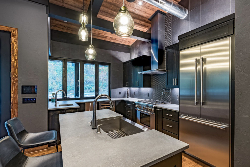 Inspiration for a large rustic l-shaped medium tone wood floor and brown floor open concept kitchen remodel in Atlanta with a farmhouse sink, shaker cabinets, black cabinets, concrete countertops, black backsplash, ceramic backsplash, stainless steel appliances, an island and gray countertops