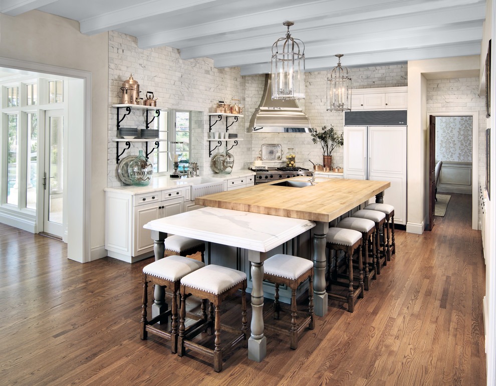 Exempel på ett klassiskt l-kök, med en rustik diskho, luckor med upphöjd panel, vita skåp, träbänkskiva, grått stänkskydd, integrerade vitvaror, mellanmörkt trägolv och en köksö