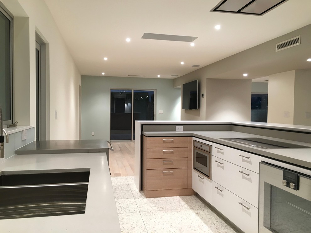 Mid-sized minimalist l-shaped concrete floor eat-in kitchen photo in Phoenix with flat-panel cabinets, an undermount sink, light wood cabinets, quartz countertops, blue backsplash, glass tile backsplash, stainless steel appliances and an island