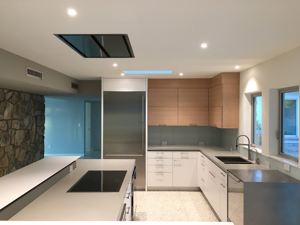 Inspiration for a mid-sized modern l-shaped concrete floor eat-in kitchen remodel in Phoenix with flat-panel cabinets, an undermount sink, light wood cabinets, quartz countertops, blue backsplash, glass tile backsplash, stainless steel appliances and an island