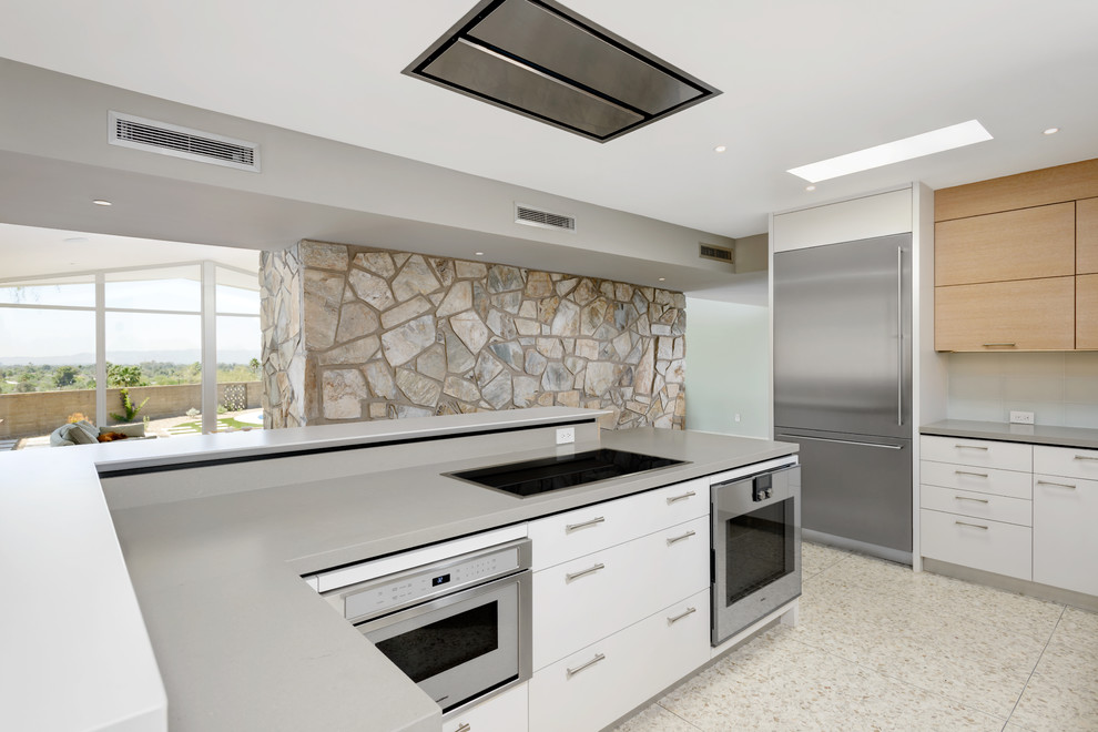 Eat-in kitchen - mid-sized 1950s l-shaped concrete floor eat-in kitchen idea in Phoenix with an undermount sink, flat-panel cabinets, light wood cabinets, quartz countertops, blue backsplash, glass tile backsplash, stainless steel appliances and an island