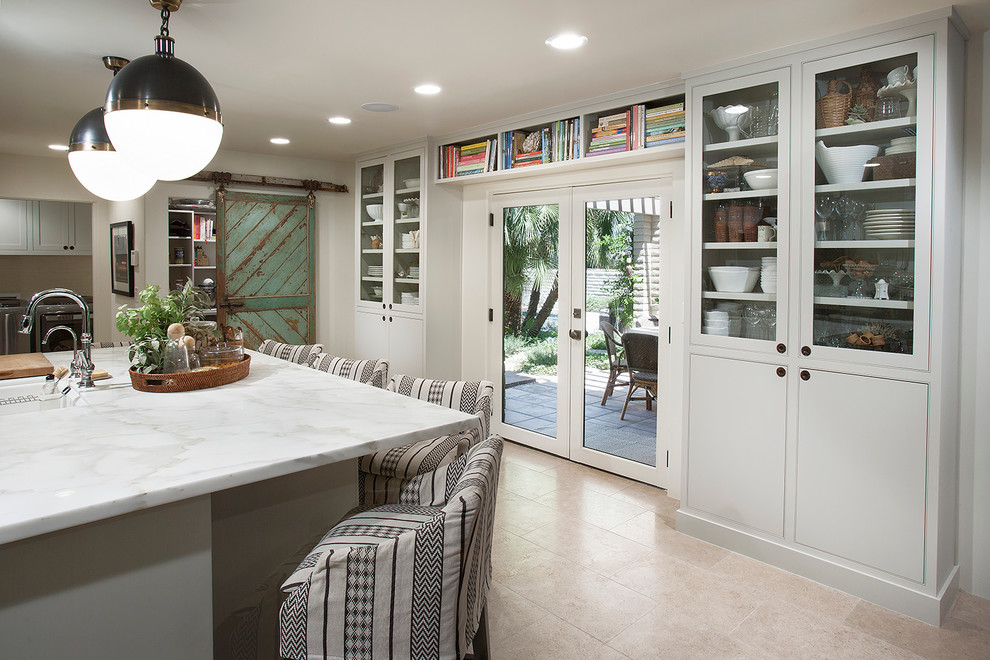 Eklektisk inredning av ett mellanstort linjärt kök och matrum, med en undermonterad diskho, släta luckor, vita skåp, marmorbänkskiva, vitt stänkskydd, stänkskydd i keramik, rostfria vitvaror, travertin golv och en köksö
