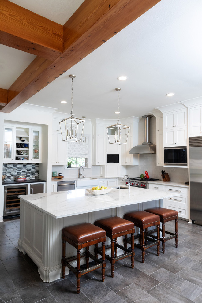 Inspiration for a traditional l-shaped kitchen in New Orleans with shaker cabinets, white cabinets, white splashback, stainless steel appliances, an island, grey floors, white worktops and exposed beams.