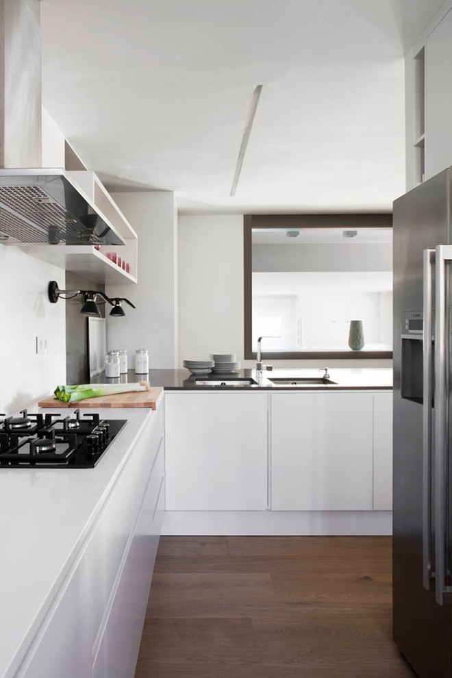 Imagen de cocinas en L contemporánea de tamaño medio cerrada sin isla con armarios con paneles lisos y puertas de armario blancas