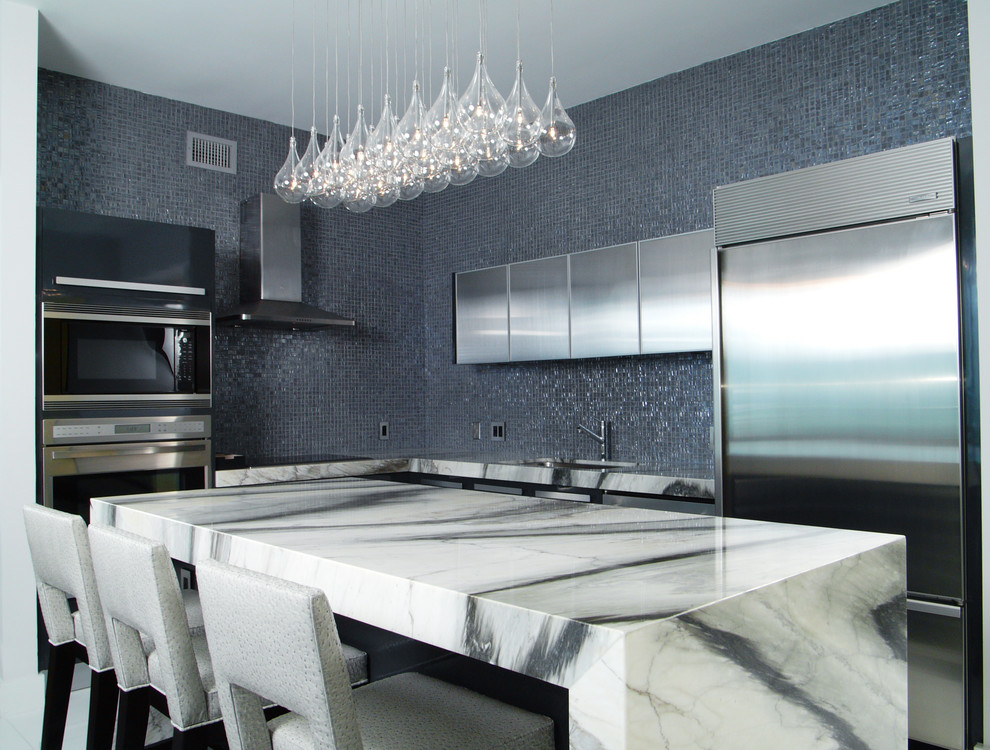 Moderne Küche in L-Form mit Unterbauwaschbecken, flächenbündigen Schrankfronten, Edelstahlfronten, Küchenrückwand in Blau, Rückwand aus Mosaikfliesen und Küchengeräten aus Edelstahl in Miami