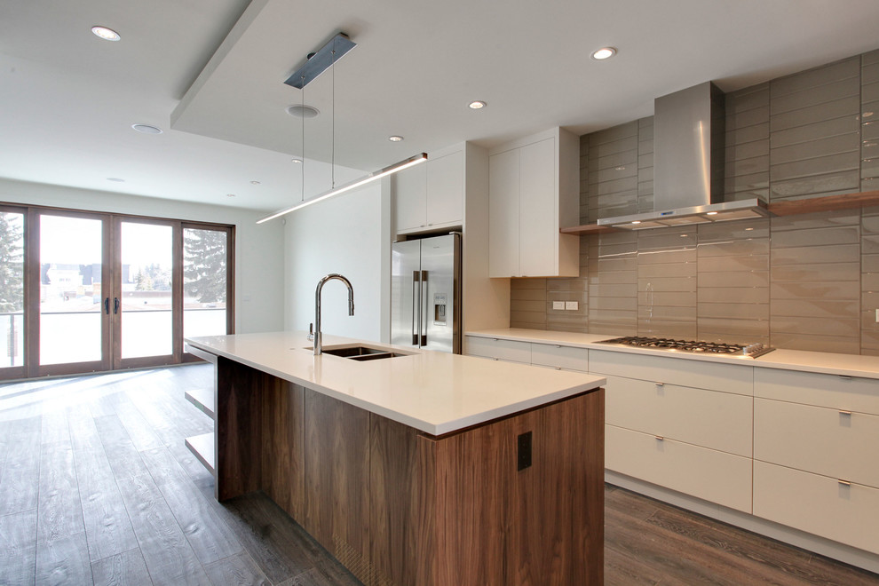 Inspiration for a medium sized modern galley open plan kitchen in Calgary with flat-panel cabinets, medium wood cabinets, an island, a submerged sink, engineered stone countertops, grey splashback, glass tiled splashback, stainless steel appliances and medium hardwood flooring.