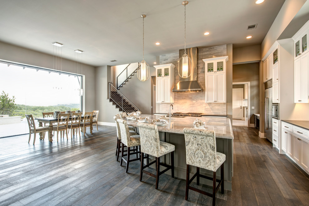 Large modern kitchen in Austin with recessed-panel cabinets, white cabinets, grey splashback, stainless steel appliances, dark hardwood flooring and an island.