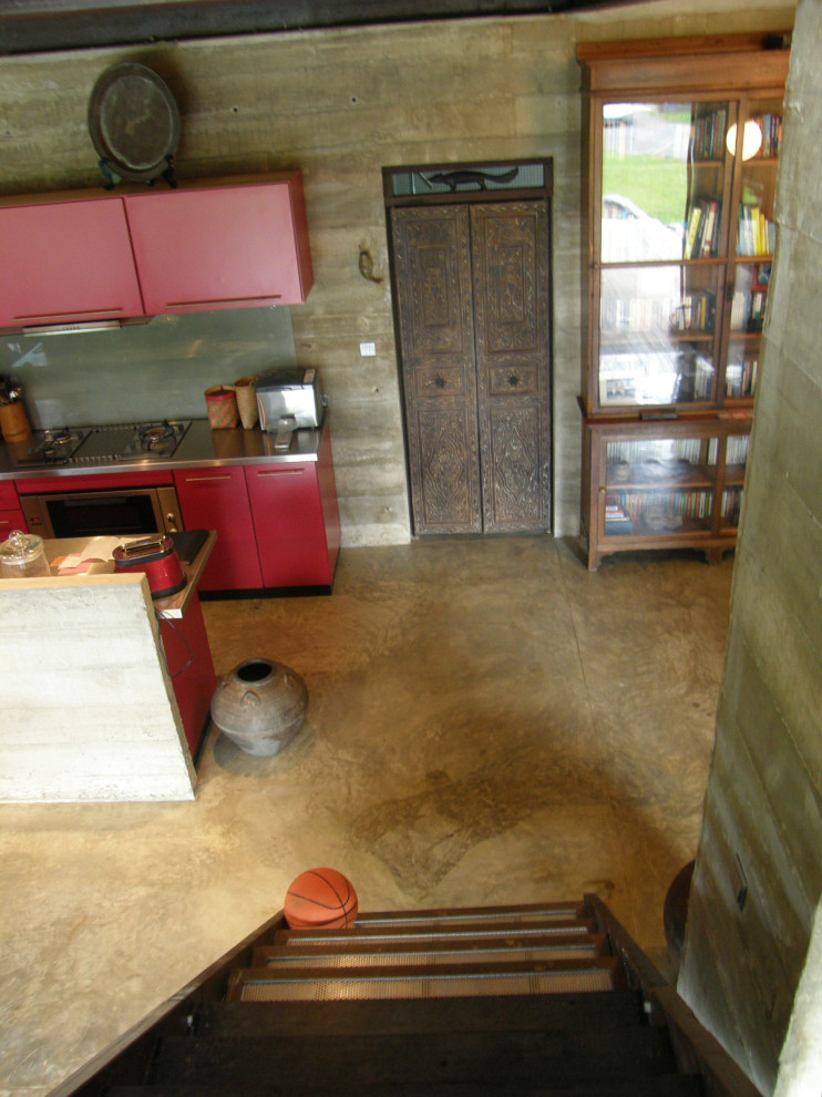Inspiration för ett mellanstort tropiskt grå grått kök, med en dubbel diskho, luckor med infälld panel, röda skåp, bänkskiva i rostfritt stål, vitt stänkskydd, glaspanel som stänkskydd, rostfria vitvaror, betonggolv, en köksö och grått golv