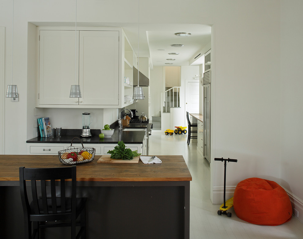Aménagement d'une cuisine parallèle moderne avec un plan de travail en bois, un placard sans porte et des portes de placard blanches.
