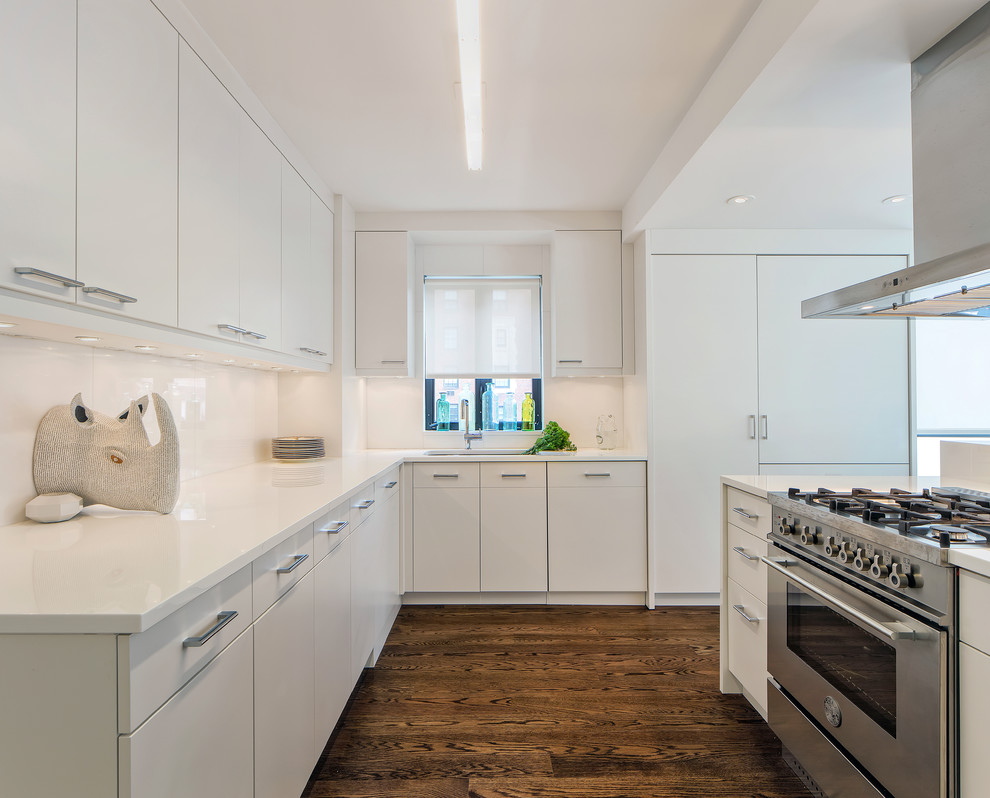 Mittelgroße Moderne Küche ohne Insel in L-Form mit flächenbündigen Schrankfronten, weißen Schränken, Küchenrückwand in Weiß, Küchengeräten aus Edelstahl und braunem Holzboden in New York