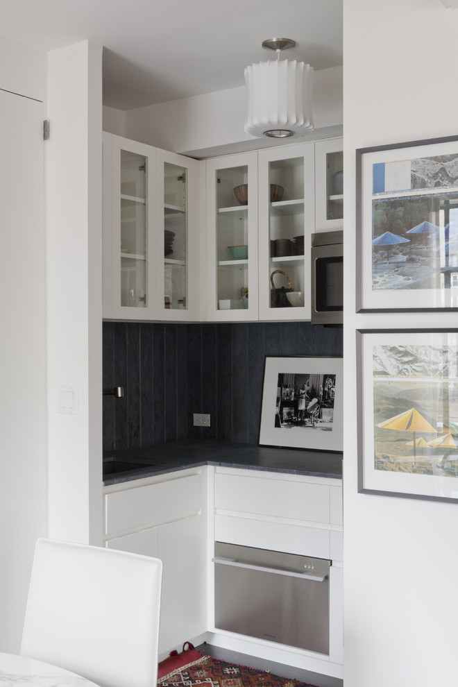 Photo of a contemporary kitchen in New York with glass-front cabinets and white cabinets.